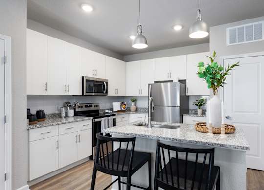 an open kitchen with white cabinets and a granite counter top