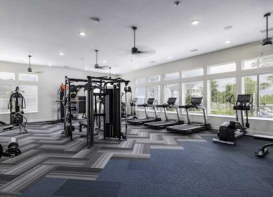 a gym with weights and cardio equipment in a building with large windows