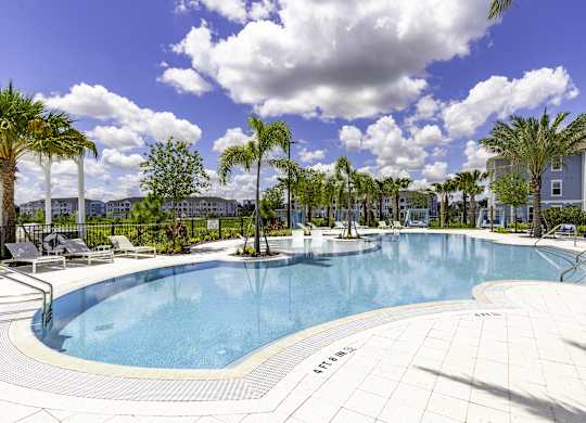 A large outdoor swimming pool surrounded by palm trees.