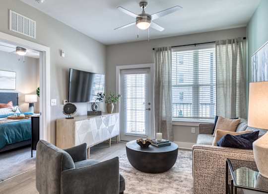 A living room with a grey couch, a black coffee table, and a ceiling fan.