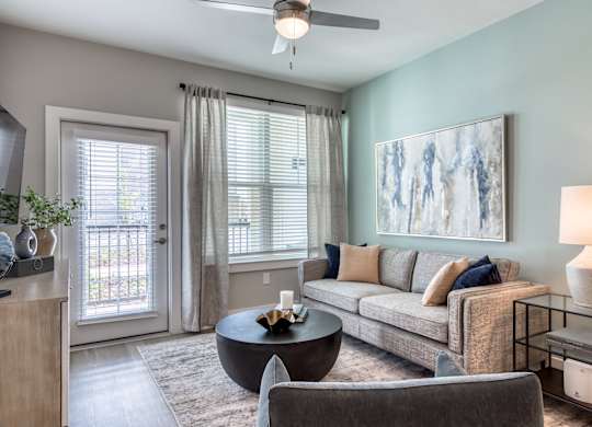 A living room with a grey couch, a coffee table, and a painting on the wall.