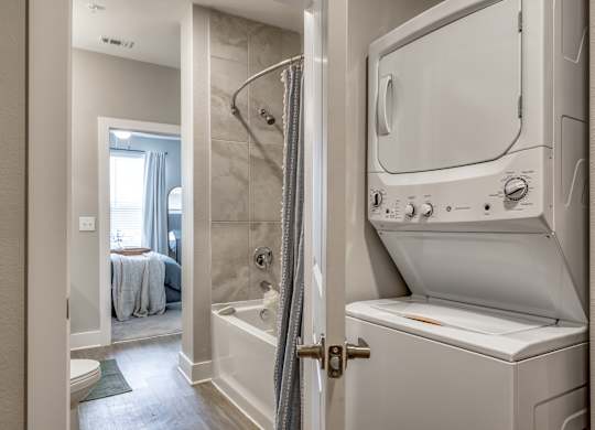 A white washing machine is in a bathroom next to a shower.