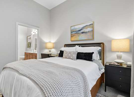 A bedroom with a large bed and a painting on the wall.