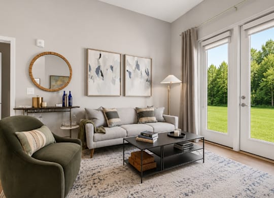 A living room with a grey couch, a brown armchair, a coffee table, and a large window with a view of a green lawn.