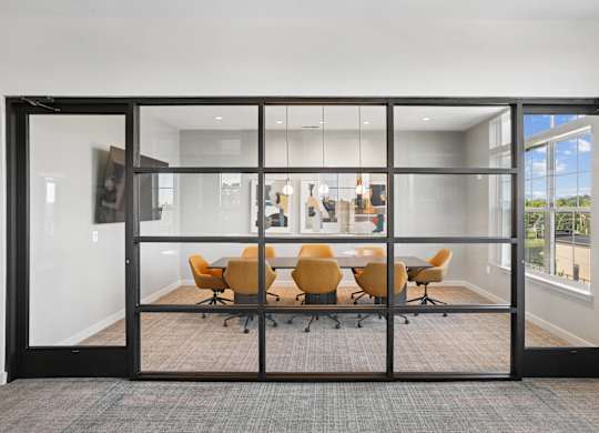 A conference room with a glass door and a table with chairs.
