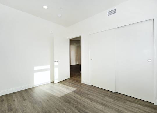 a bedroom with white walls and wood floors