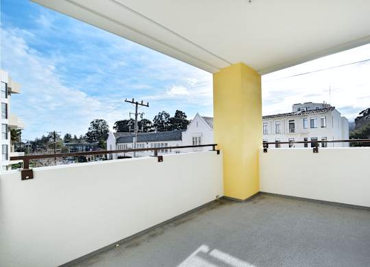 A yellow column stands in the middle of a white-walled, open balcony.