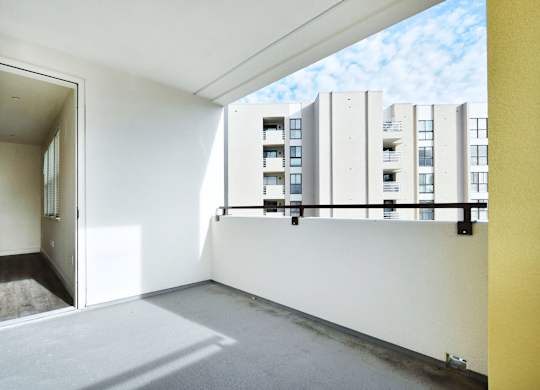an empty room with a balcony overlooking an apartment building