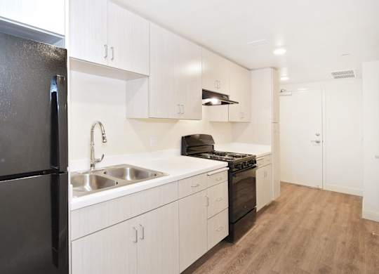 a kitchen and a living room with white walls and a wood floor