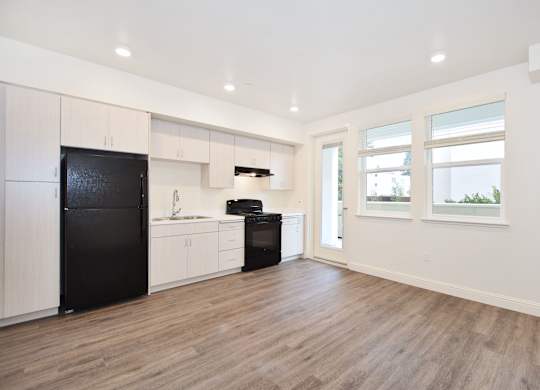 A kitchen with black appliances and wooden floors.