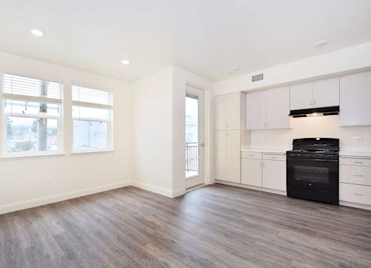 an empty kitchen with white cabinets and a black stove and refrigerator