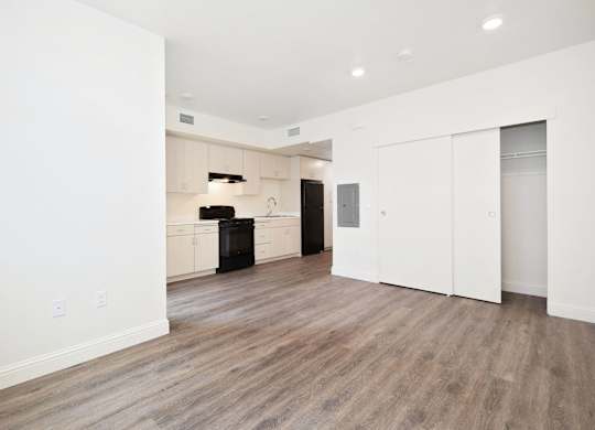 A spacious room with wooden flooring and white walls.