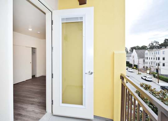 A white door with a glass panel is open to a balcony.
