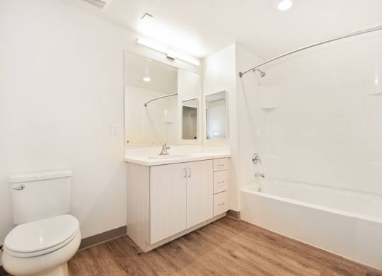 A white bathroom with a toilet, sink, and bathtub.