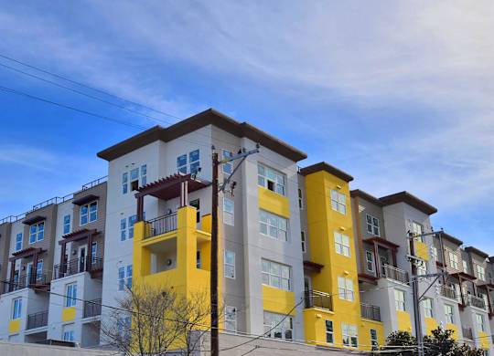 a row of apartment buildings with yellow and white facade and a blue sky