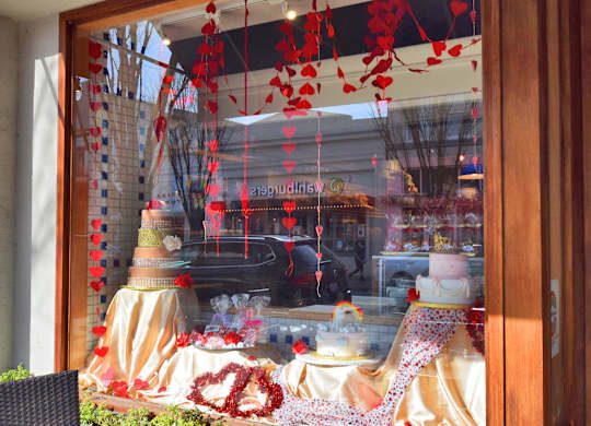 A window display with a cake and red decorations.