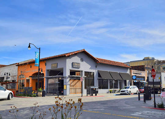 A white car is parked in front of a building with a red roof.