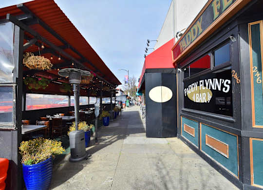 a sidewalk in front of a restaurant with a sidewalk sign in the window