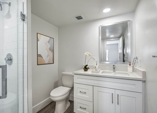 A white bathroom with a toilet, sink, and mirror.