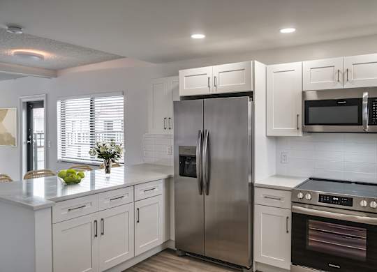 A kitchen with white cabinets and stainless steel appliances.