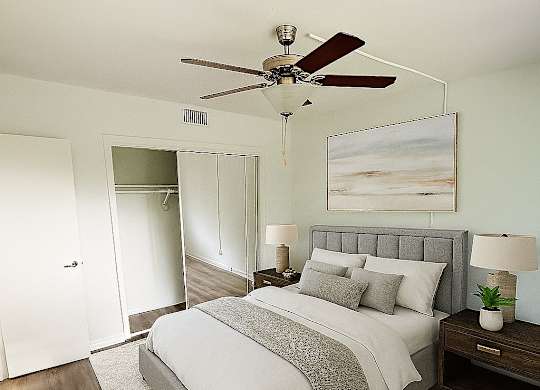 A bedroom with a bed, nightstand, and a ceiling fan.