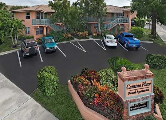 Cars parked in a parking lot in front of a building with a sign that says Cemino Place Rental Apartments.