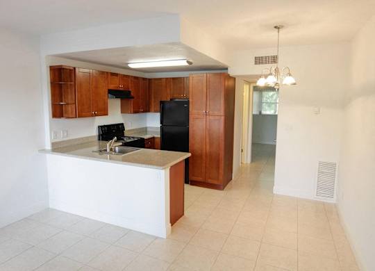 A kitchen with a black refrigerator and wooden cabinets.