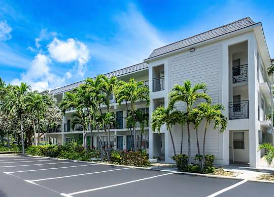 A white building with a parking lot in front of it.