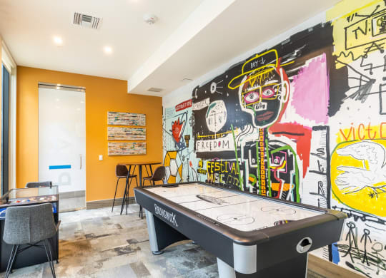 a game room with a pool table and graffiti on the wall