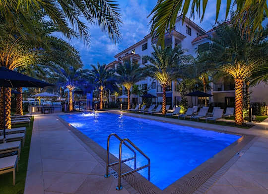 a swimming pool at night with palm trees