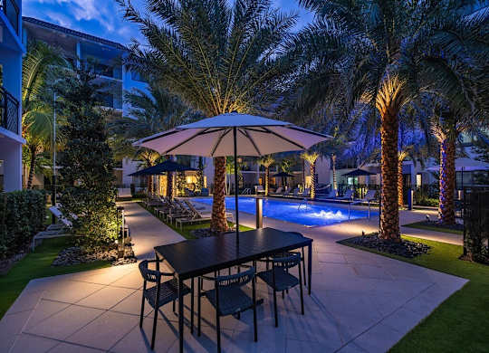a table with an umbrella next to a pool at night