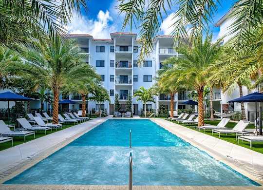 a large pool with palm trees in front of an apartment building