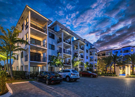 an apartment building at night with cars parked in front of it