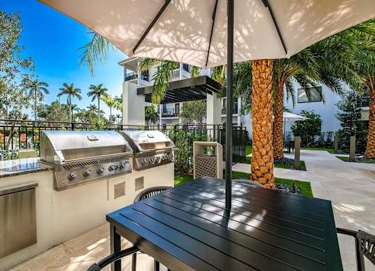 a patio with a barbecue grill and a table with an umbrella
