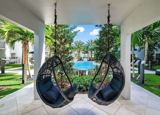 two swinging chairs on a porch overlooking a swimming pool