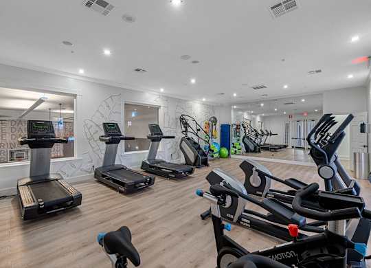 the gym has plenty of cardio equipment and a wall mural of graffiti
