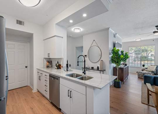 an open kitchen and living room with white cabinets and a sink