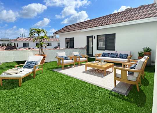 a backyard patio with wooden furniture and a white house