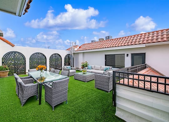 A patio with a table and chairs is surrounded by a white wall.