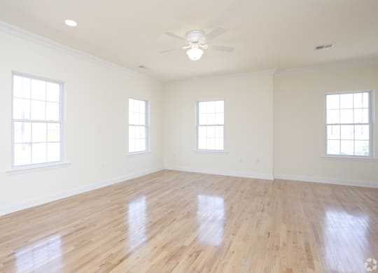 an empty room with a ceiling fan and three windows