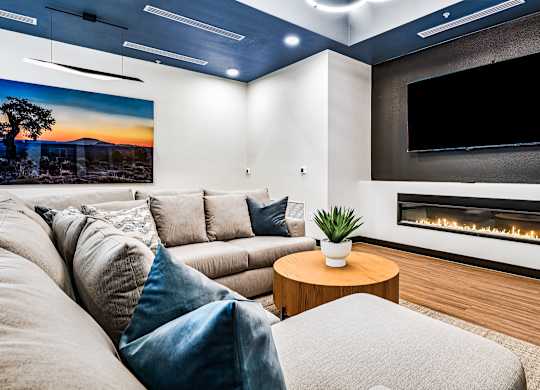 A modern living room with a grey couch, a wooden coffee table, and a fireplace.