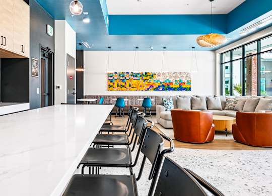 A long white table with black chairs is in the foreground of a room with blue walls.
