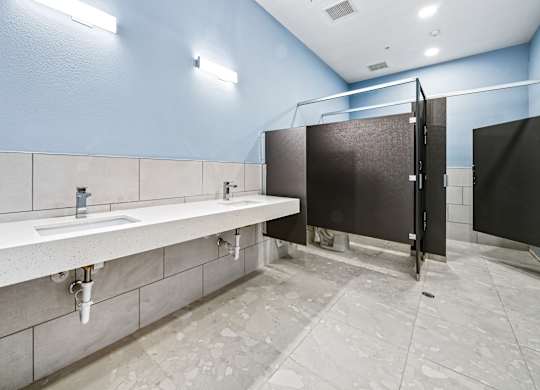 A public restroom with a row of sinks and a row of stalls.