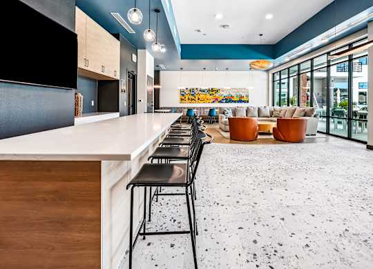 A modern kitchen with a long bar and chairs.