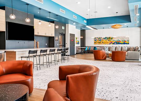 A modern lounge area with orange chairs and a white and blue color scheme.