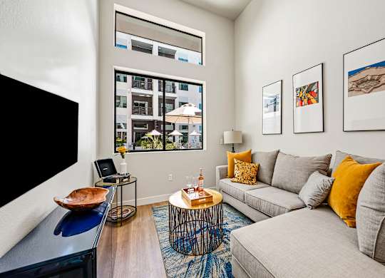 A living room with a grey couch, a coffee table, and a large window.