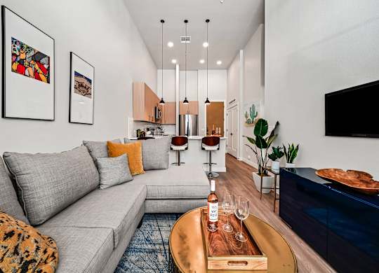 A modern living room with a grey sofa, a wooden coffee table, and a TV on the wall.