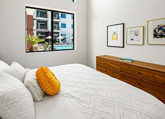 A bedroom with a bed, pillows, a nightstand, and pictures on the wall.