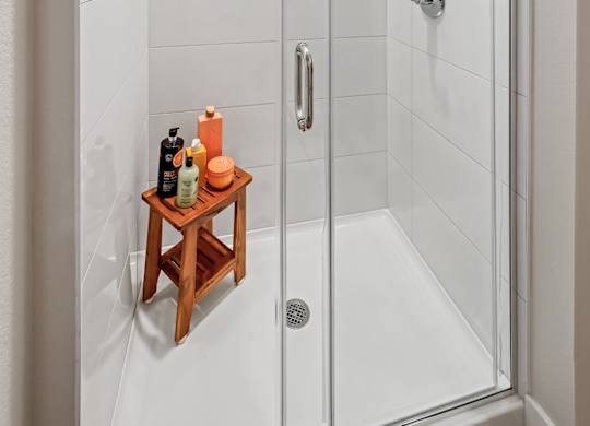A shower with a shelf and a glass door.