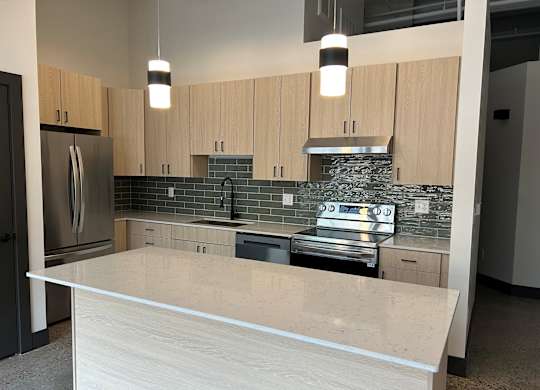 A modern kitchen with a large island and stainless steel appliances.